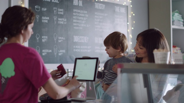 冰淇淋店的员工在平板电脑上为顾客办理信用卡付款视频素材