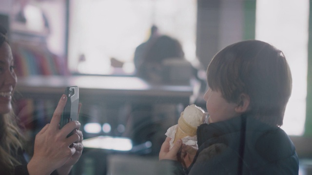 妈妈拍下了她儿子用手机吃冰淇淋蛋卷的照片视频素材