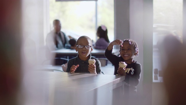 两个非裔美国兄弟姐妹一边吃冰淇淋，一边玩他们的软糖蠕虫视频素材