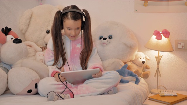 穿着独角兽睡衣的女孩坐在她的房间里，在会议上与助听器愉快地交谈视频下载