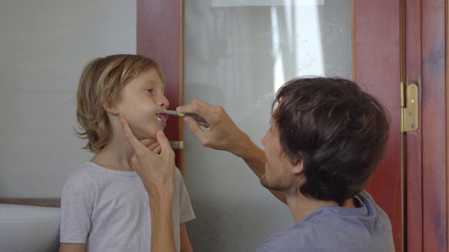 一个男人给他的小儿子刷牙。牙齿保健的概念视频素材