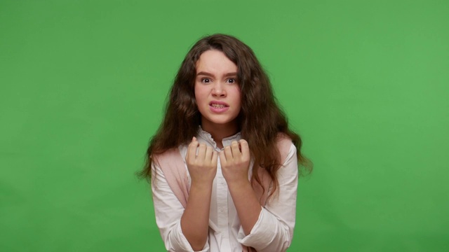一个穿着白衬衫的黑发少女对青春期的问题感到紧张，咬指甲和手指视频素材