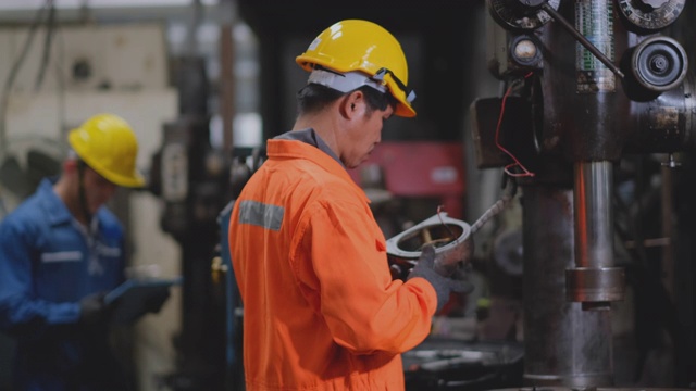 身穿橙色制服的技术员或工程师在工厂后台与其他工人一起维护和解决机器的问题视频素材