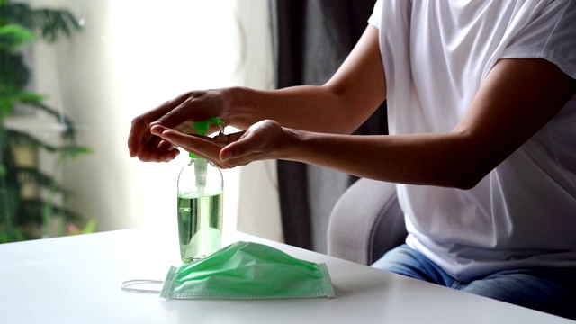 年轻女子使用酒精凝胶洗手液泵，以避免感染冠状病毒和细菌前戴手术口罩视频素材