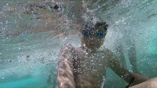 快乐的黑发男孩正在游泳池的水下游泳视频下载