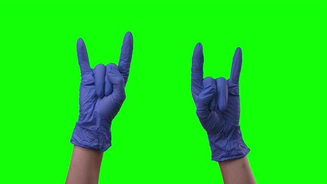 医生女手上戴着蓝色手套，正露出岩石的标志，酷酷的。绿色的屏幕。近距离视频下载