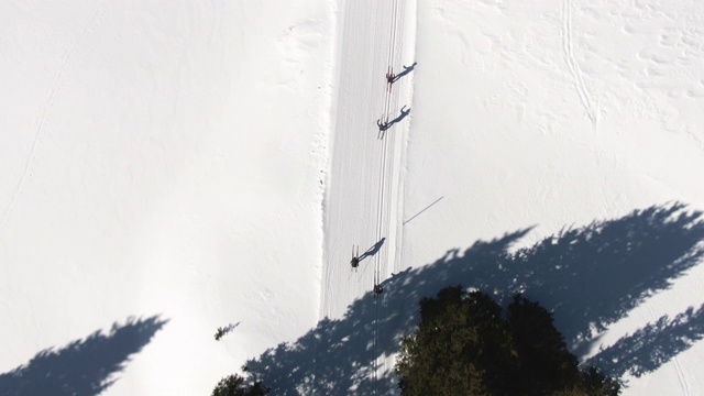 在一个阳光明媚的冬日，科罗拉多州，一组四名成年人在雪道上越野滑雪视频下载