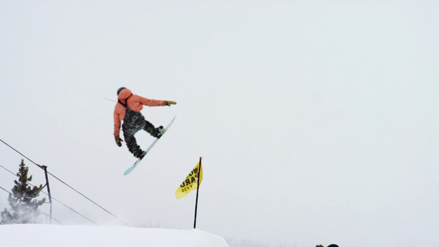 完整的冬季装备滑雪板完成一个“前侧360尾巴抓取”在博尔德附近的埃尔多拉滑雪度假村跳跃的技巧，科罗拉多州在一个下雪的，阴天视频素材