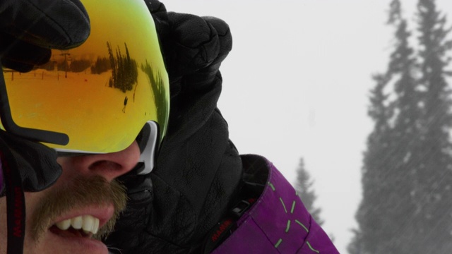 慢动作拍摄三十多岁，男性滑雪板运动员微笑，戴上他的护目镜准备在一个阴天的冬天滑雪板视频下载