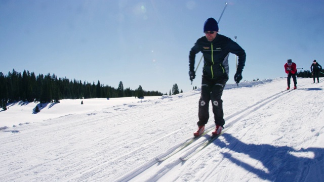 一组四名成年人的慢动作拍摄，因为他们在一个阳光明媚的冬天，在科罗拉多滑雪在一条线下山视频下载