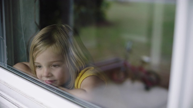 可爱的小女孩望着窗外。视频下载