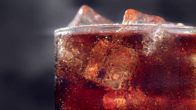 微距慢镜头玻璃与冰块和气泡的新鲜碳酸可乐苏打饮料，近视频素材
