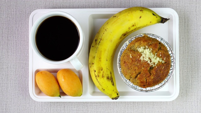 咖啡休息时间的香蕉杯蛋糕、熟香蕉、玛丽安李子和黑咖啡。视频下载