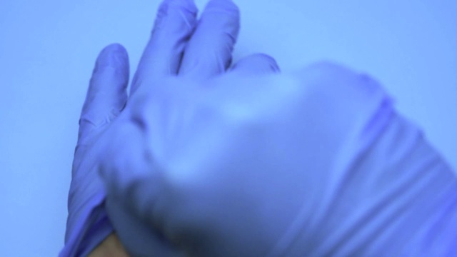 医生戴着乳胶手套，背景是蓝色的视频素材