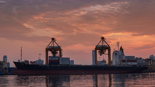 4K延时:黄昏时分，工作吊桥在码头商埠或集装箱仓库将集装箱装到集装箱船，用于商业物流、进出口、海运或运输。视频素材