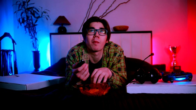 年轻英俊的男人戴着眼镜躺在床上看电视视频下载