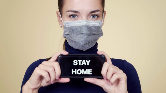 年轻女子的肖像在医疗面具显示电话与题词留在家里视频下载