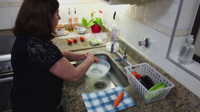 成年妇女在家庭厨房清洗蔬菜(胡萝卜)，然后把它们放入冰箱视频下载