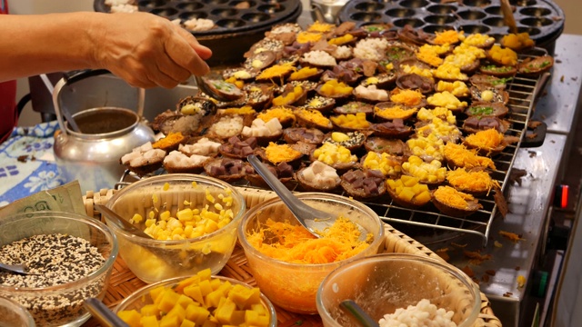 异国情调的东方美味甜点，不同寻常的色彩斑斓的传统菜肴在柜台上的集市与街头小吃。曼谷的晚间美食广场，烹饪之都。夜市。视频素材