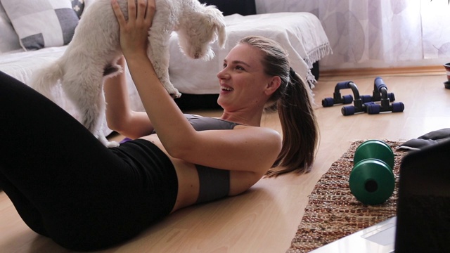 一只马耳他犬在女主人在家锻炼时打扰她视频素材