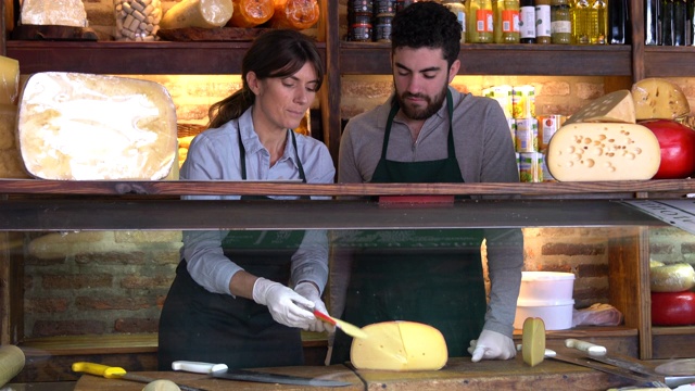 快乐的老板在熟食店教一个新员工奶酪视频下载