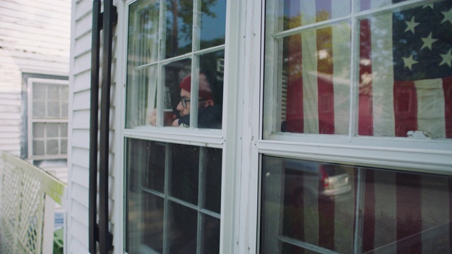 一个年轻人拿着一瓶啤酒凝视着窗外。视频素材