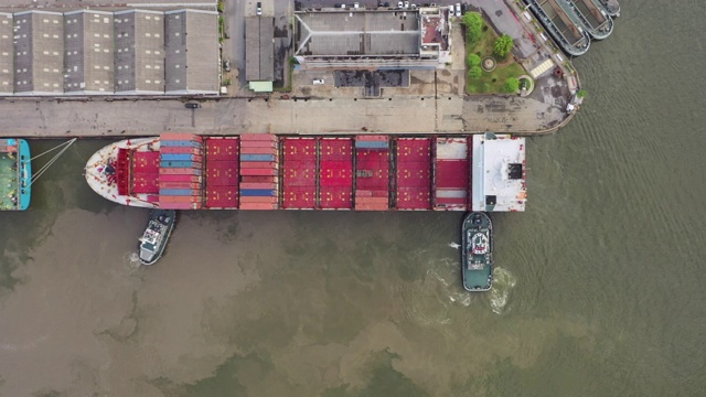 4K时间延时:航拍俯视图，拖船拖着集装箱货船到码头商港或集装箱仓库进行商务物流，进出口，运输或运输。视频素材