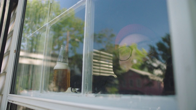 一名男子一边喝着啤酒，一边看着窗外。视频素材