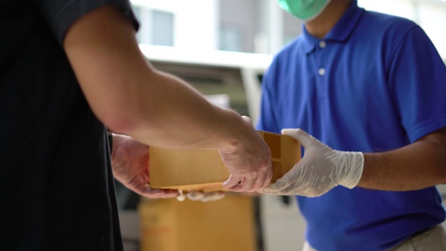 近距离观察亚洲蓝色快递员戴医用橡胶手套送包裹给客户，在发货前。4k分辨率和慢动作拍摄。视频素材