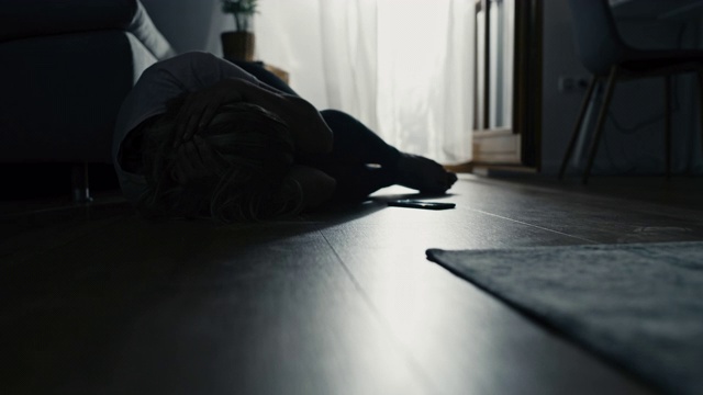 一名女子躺在地板上，头部被疼痛掩盖视频下载
