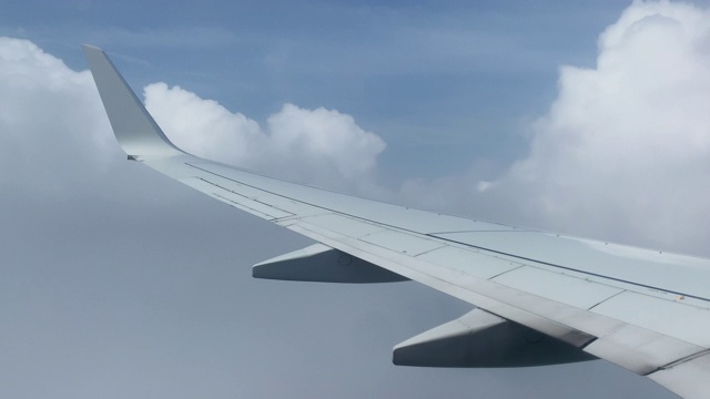 在一个阳光明媚的日子，从一个商业航空公司的飞机飞过云层和降落的机翼上的观点视频素材