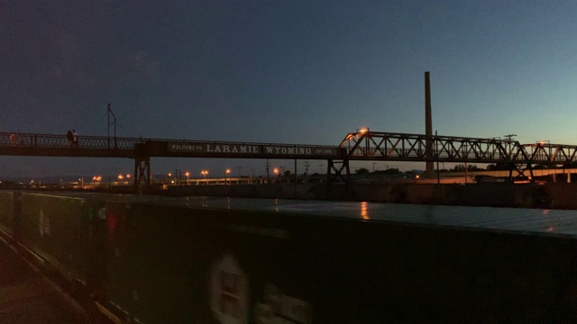 日落/日出时，怀俄明州拉勒米的一列火车沿着步行桥下的轨道行驶视频下载
