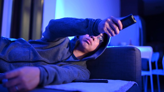 一个亚洲华人中年人在黑暗中独自在家玩电子游戏，戴着耳机和游戏控制器视频素材
