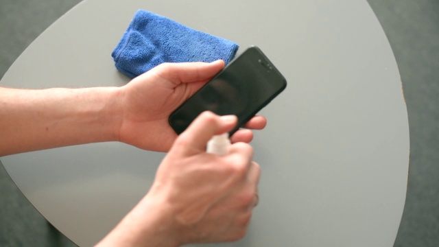 一名男子在室内用消毒剂清洁智能手机视频下载
