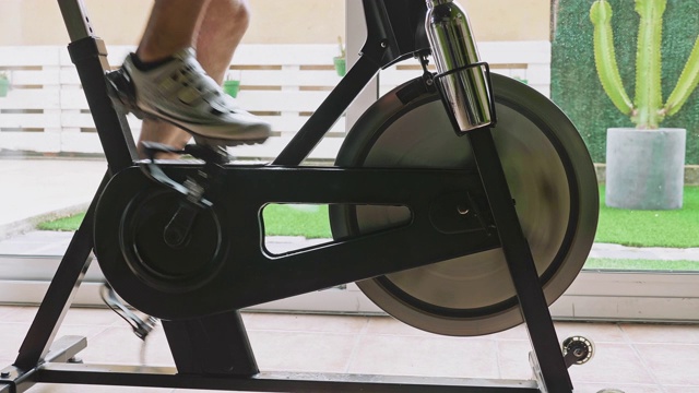 慢动作低截面视频的成熟男子在锻炼自行车在家视频素材