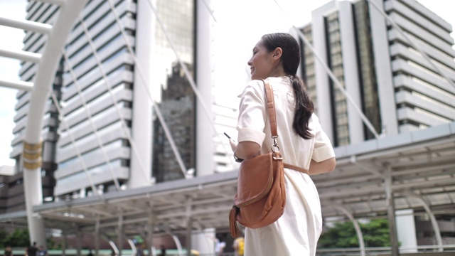 亚洲女商人在步行上班时使用智能手机视频素材