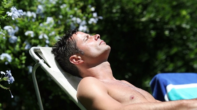 英俊的男人躺在阳光下晒太阳视频下载