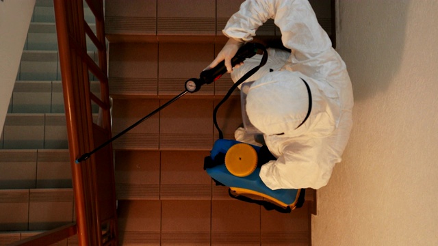 一名身着防护服的妇女正在为住宅楼空间消毒视频素材
