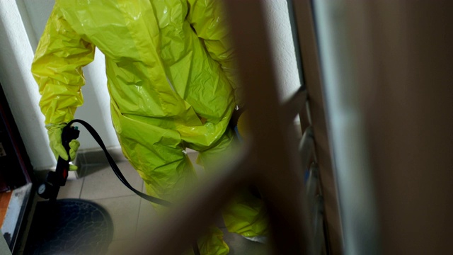 一名身着防护服的妇女正在为住宅楼空间消毒视频素材