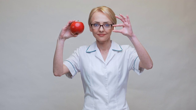 营养学家医生健康生活方式概念-拿红苹果和药或维生素丸视频素材