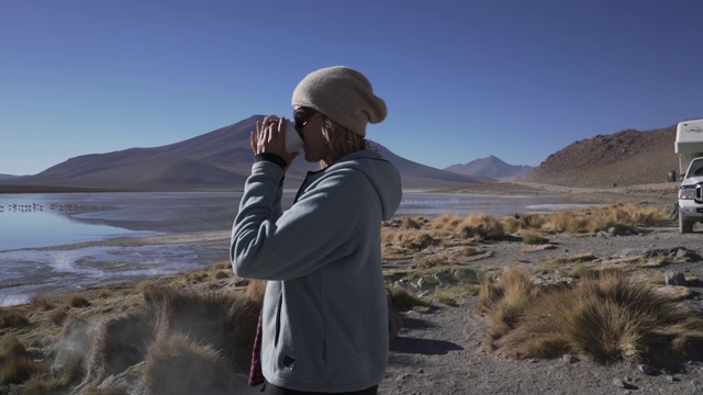 一个女人站在安第斯山脉冒着热气的湖泊前视频下载