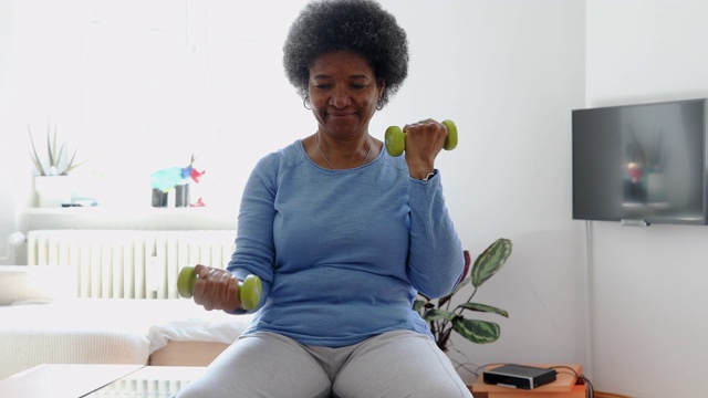 活跃的老年妇女在家里用哑铃锻炼视频下载