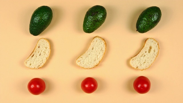 定格动画的成熟鳄梨在黄色的背景，番茄和面包。烹饪和食用素食三明治。视频下载