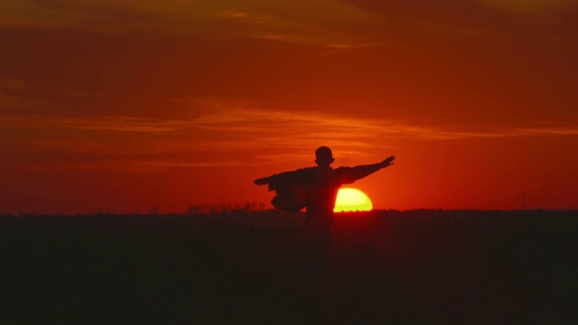 一个男孩正穿过田野。太阳正在地平线下落下。4 k视频素材