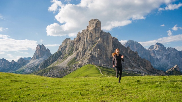 一个健康的女人在山上的草地上跑着视频素材