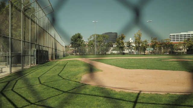 在2020年4月COVID-19期间，空的棒球菱形击球穿过铁丝网围栏，没有人视频下载