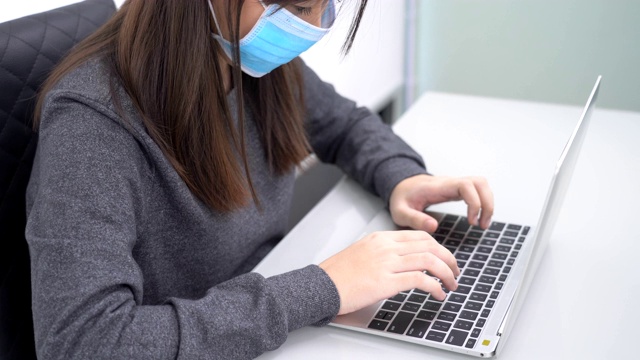 在电脑前工作的女人。女人用手在笔记本电脑键盘上打字，呆在家里的概念视频素材