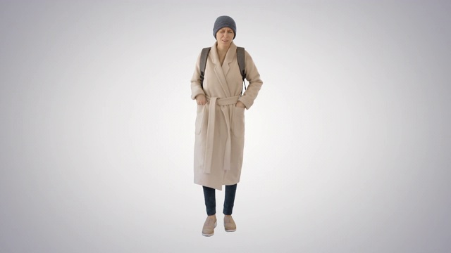 穿着大衣的女人在梯度背景上行走和咳嗽视频下载