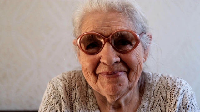 慢动作肖像，一个快乐的老年妇女与灰色头发和眼镜。视频素材