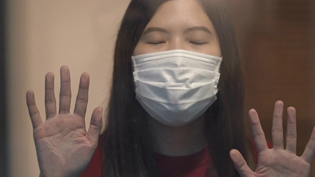 亚洲妇女通过窗口自我隔离检查冠状病毒或Covid-19视频素材